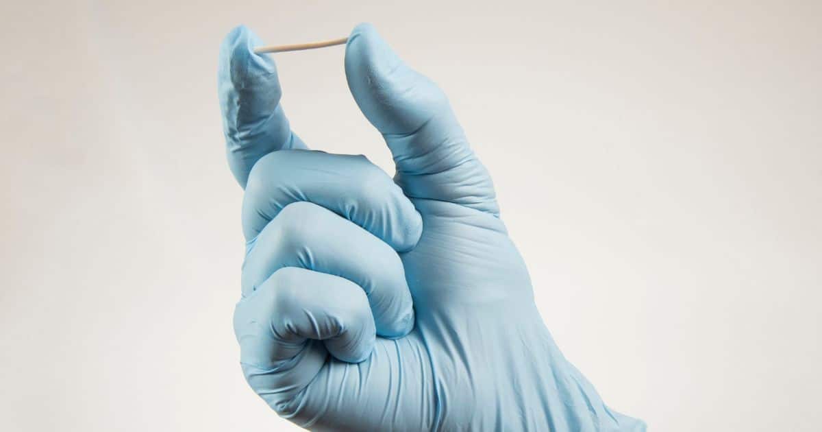 Médico segurando implanon com a ponta dos dedos